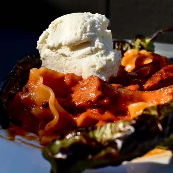 Roasted pepper stuffed with red sauce and meat, topped with a scoop of white cheese.